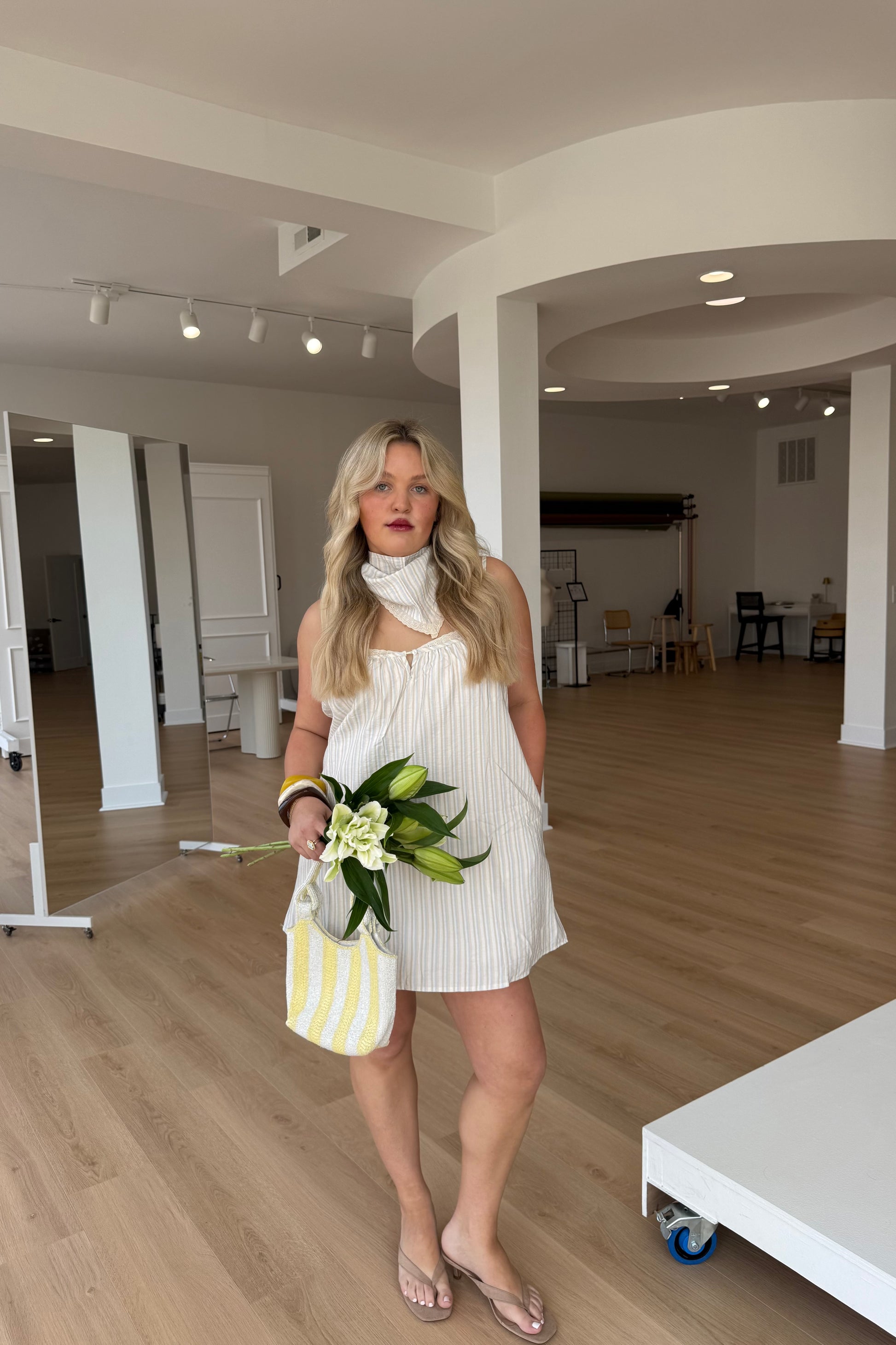 Woman in a white dress holding flowers in a modern indoor setting