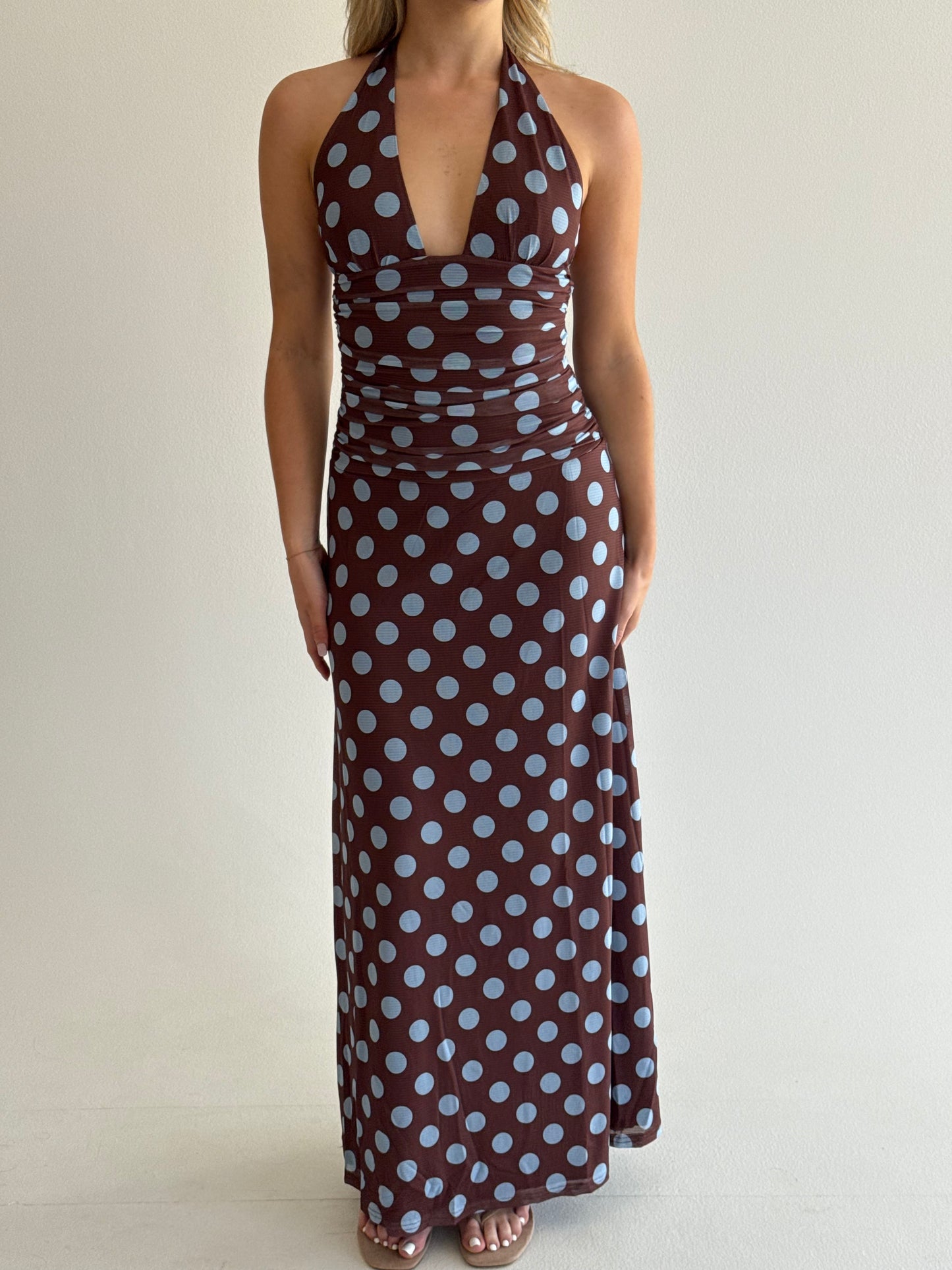 Person holding a brown fabric with white polka dots against a plain background