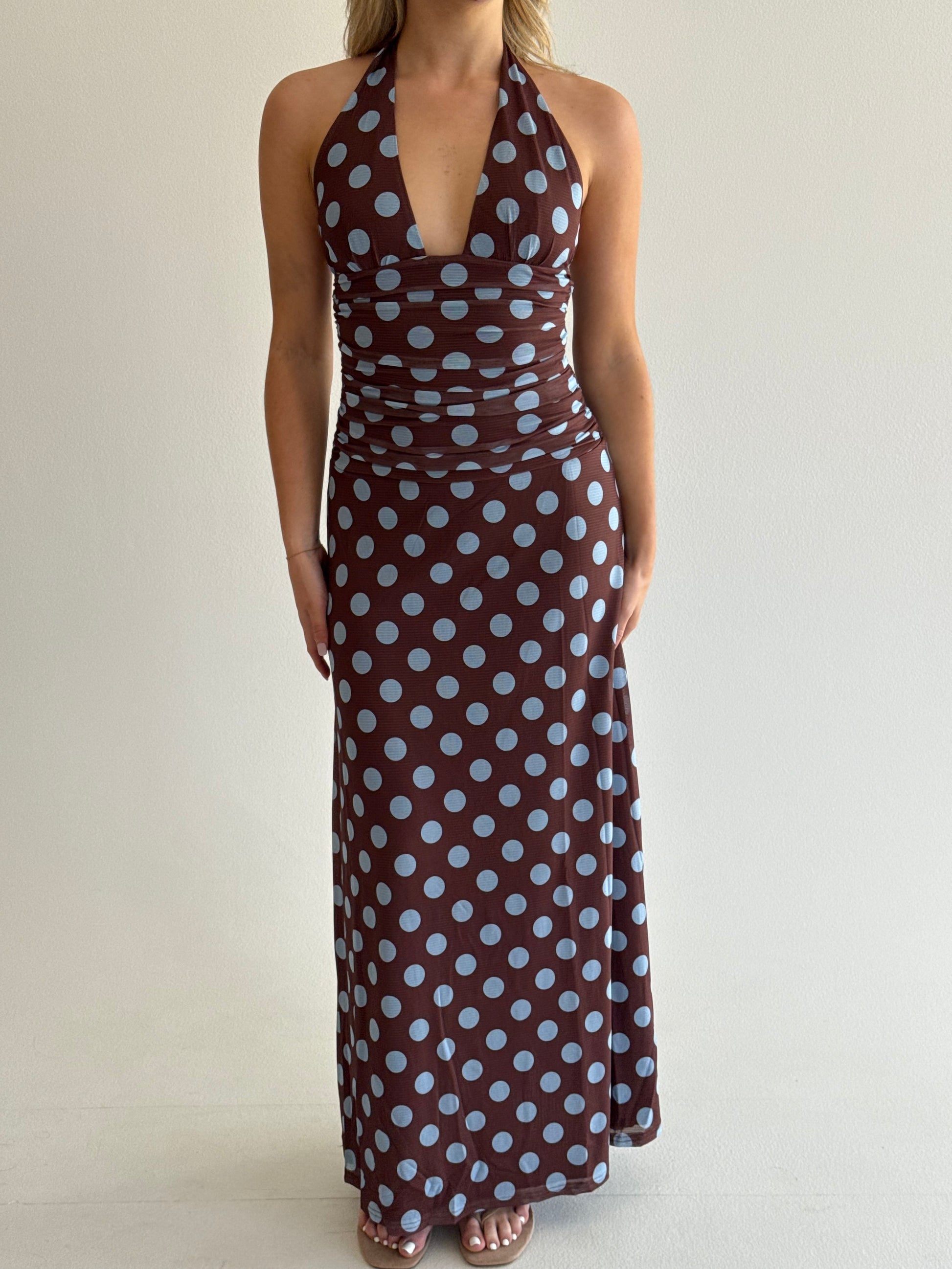 Person holding a brown fabric with white polka dots against a plain background