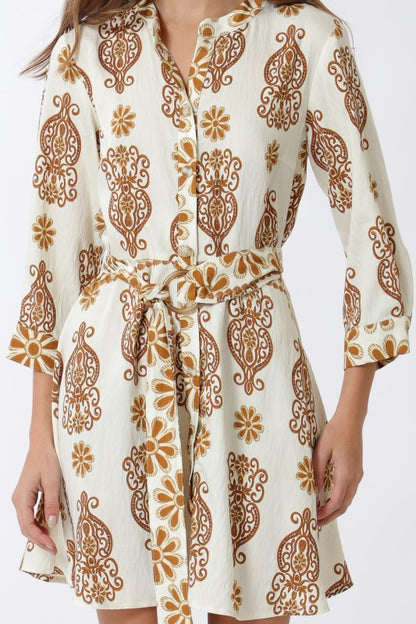 White dress with brown floral pattern worn by a person on a white background