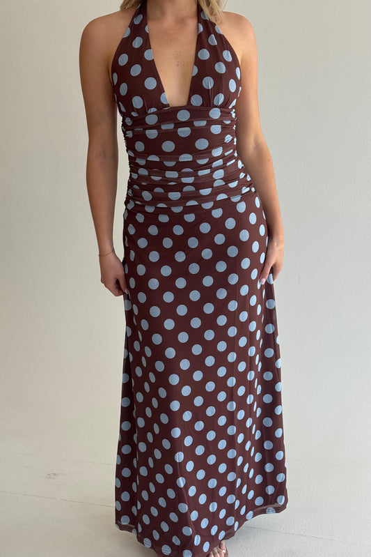 Woman wearing a brown dress with white polka dots on a plain background