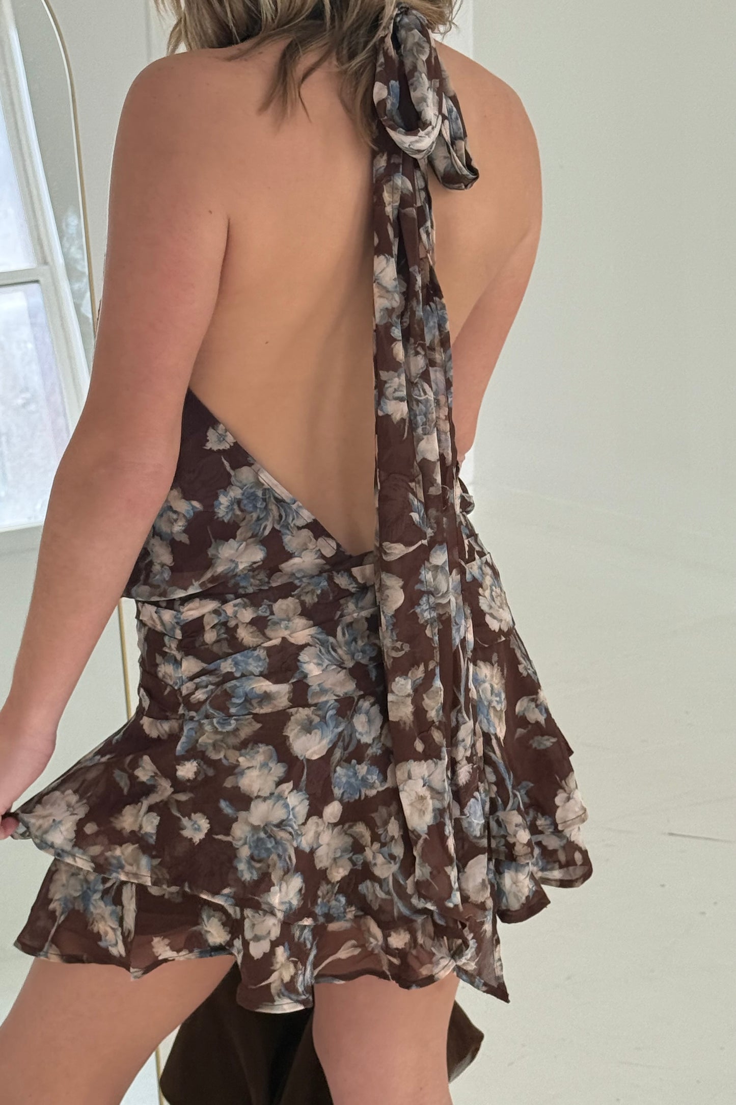 Floral brown mini dress with open back and ruffled hem, perfect for summer outings.