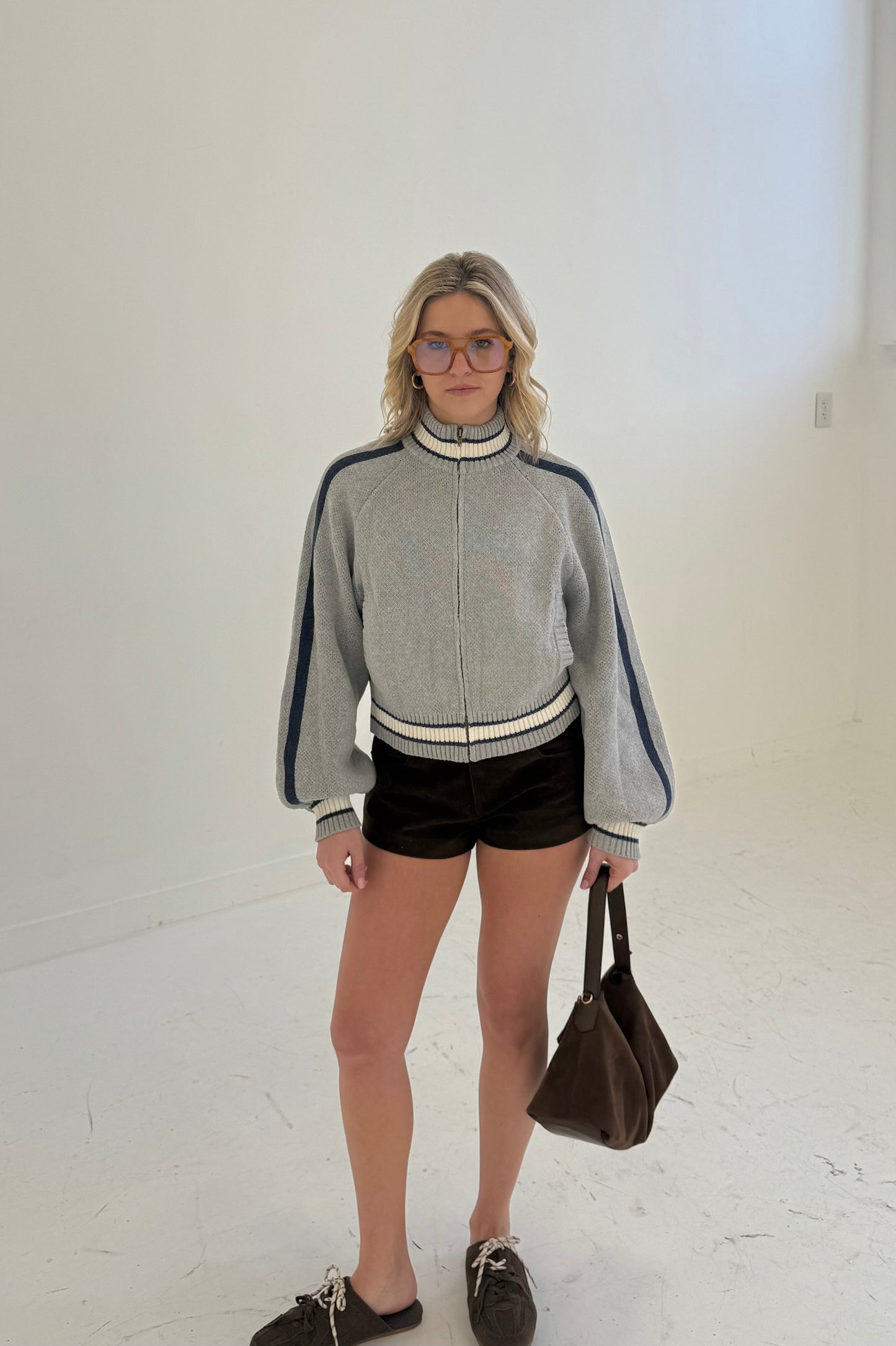 Women’s gray zip-up sweater with navy stripes, featuring a high collar and balloon sleeves.