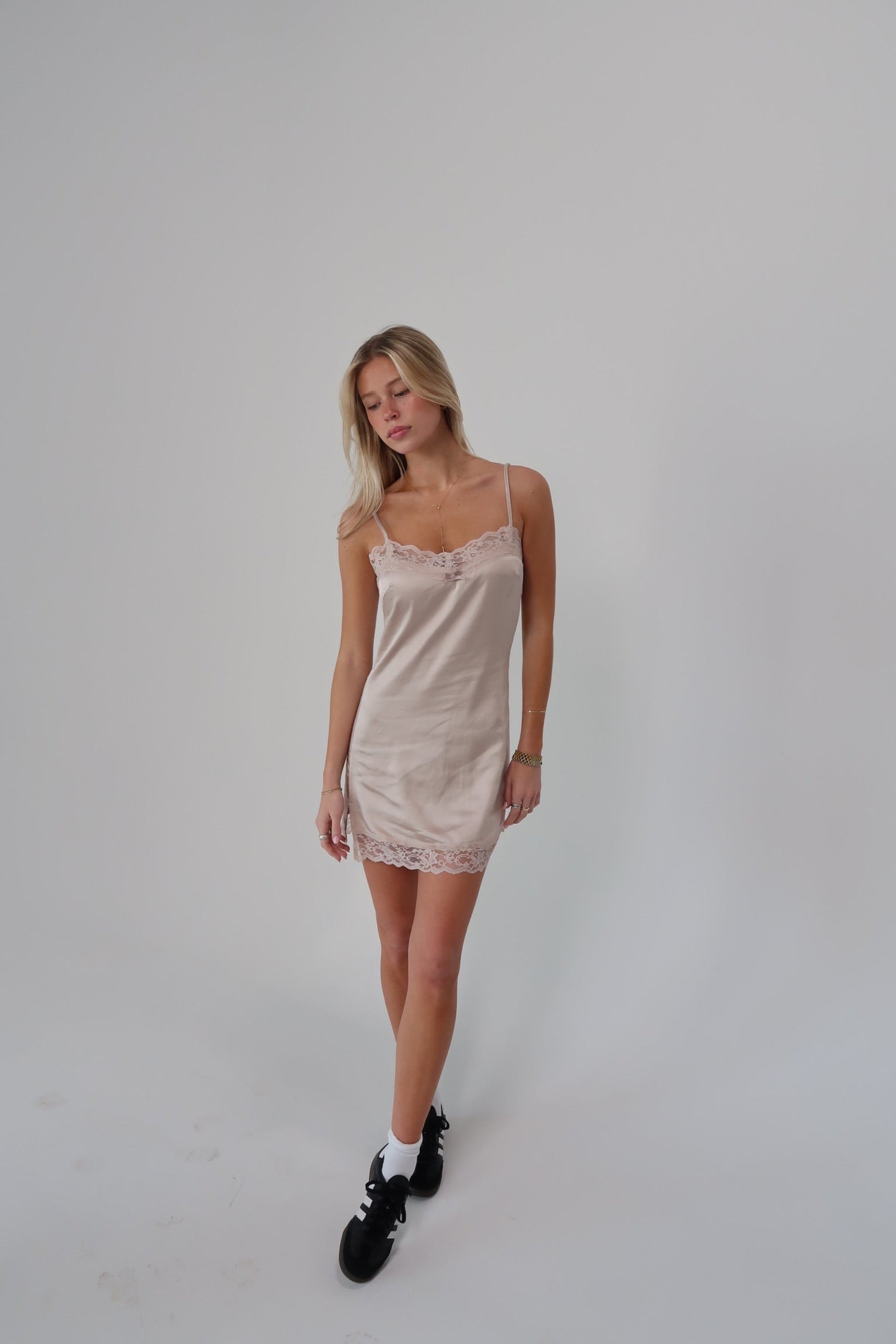 Light pink satin slip dress with lace trim on the neckline and hem.