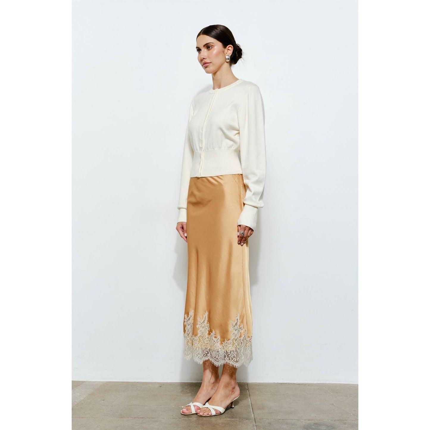 Cream cropped sweater paired with a satin gold skirt featuring lace trim, perfect for elegant occasions.