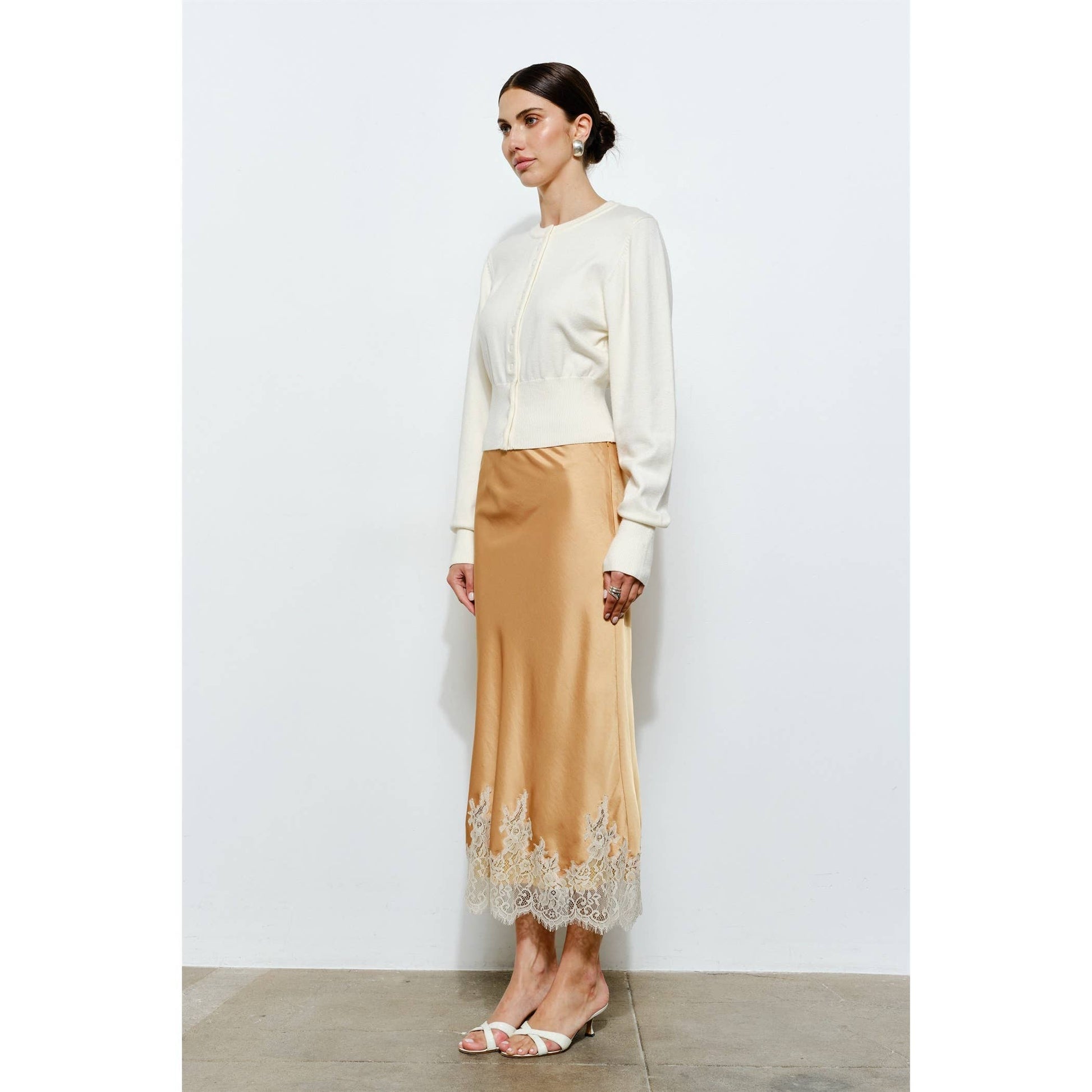 Cream cropped sweater paired with a satin gold skirt featuring lace trim, perfect for elegant occasions.