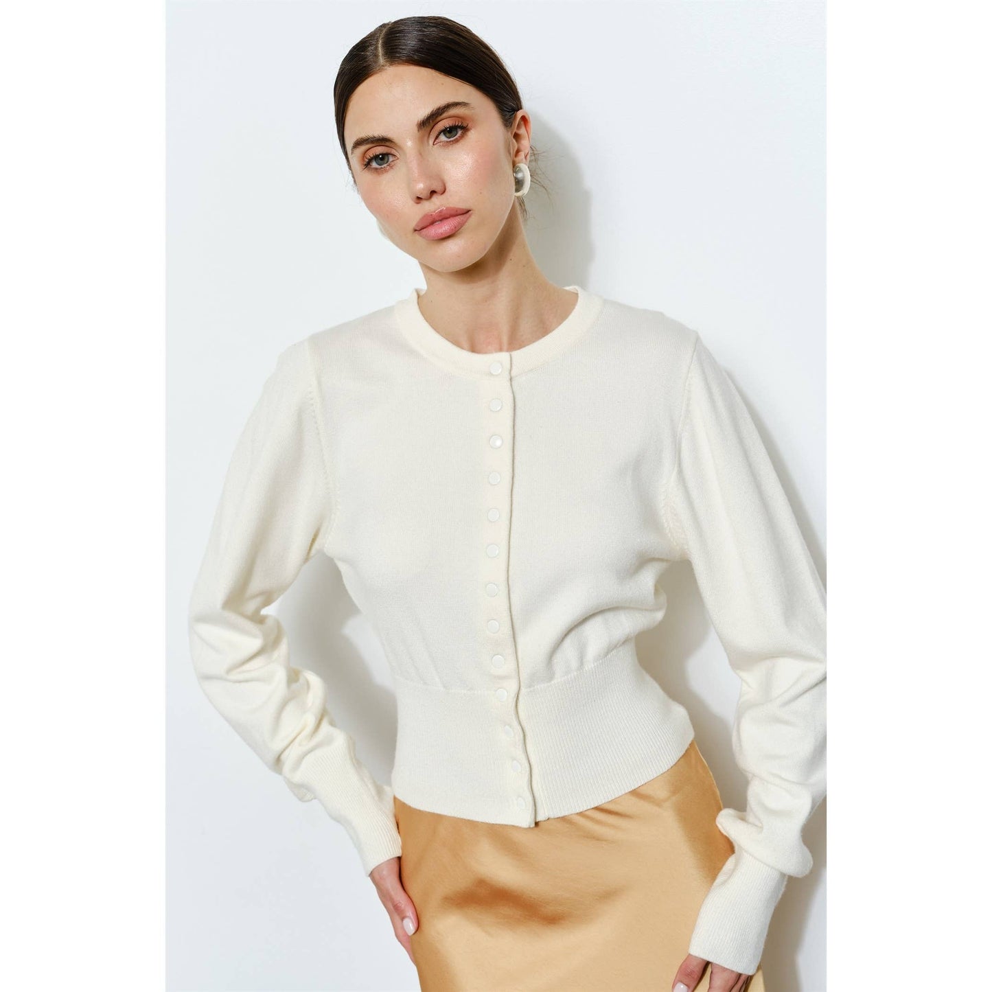 Cream button-up cardigan made of soft knit material, featuring a fitted waist and long sleeves.