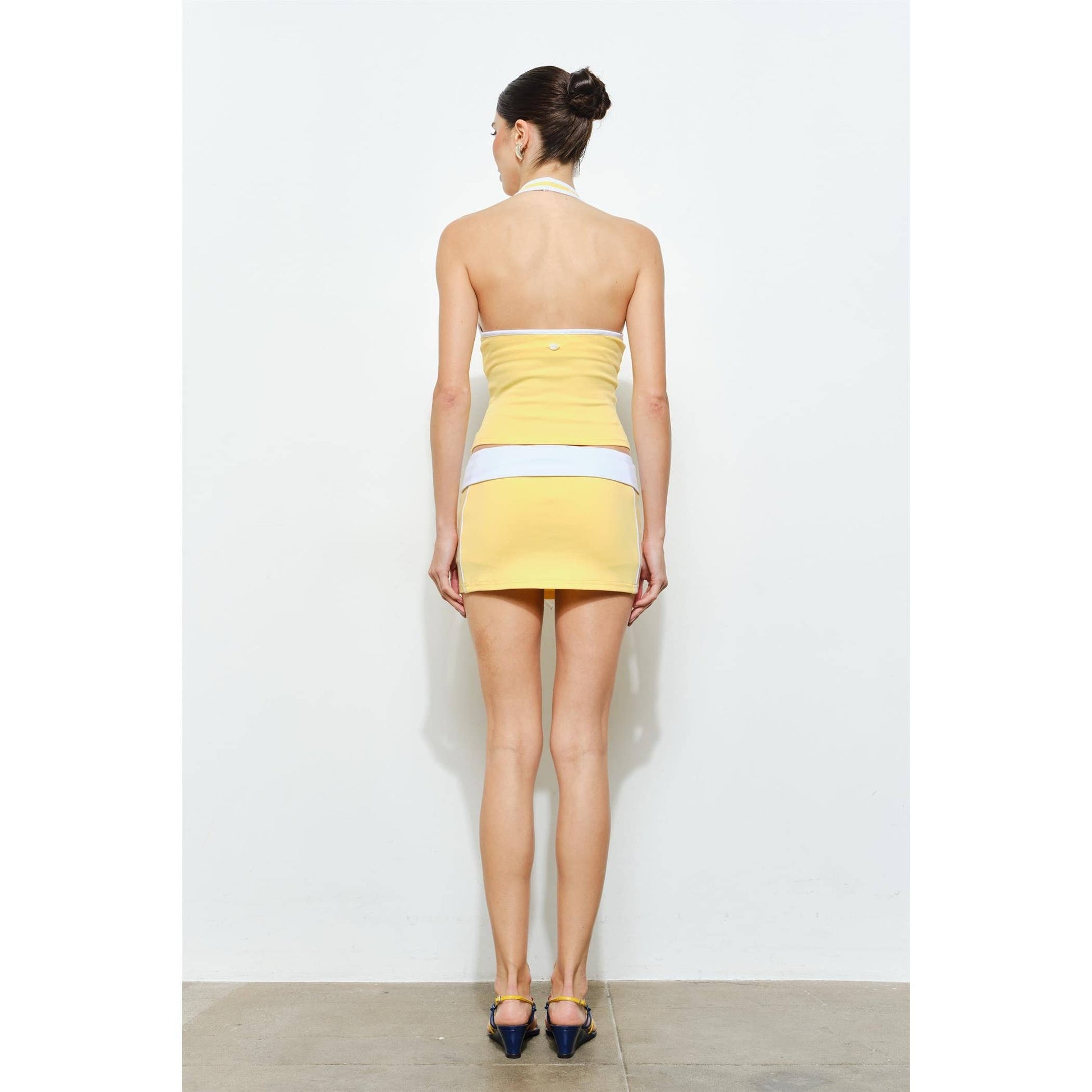 Woman wearing a yellow and white dress against a white background