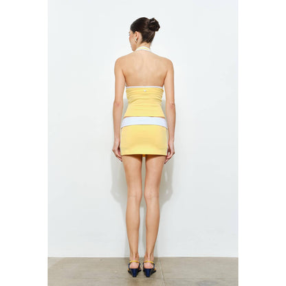 Woman wearing a yellow and white dress against a white background