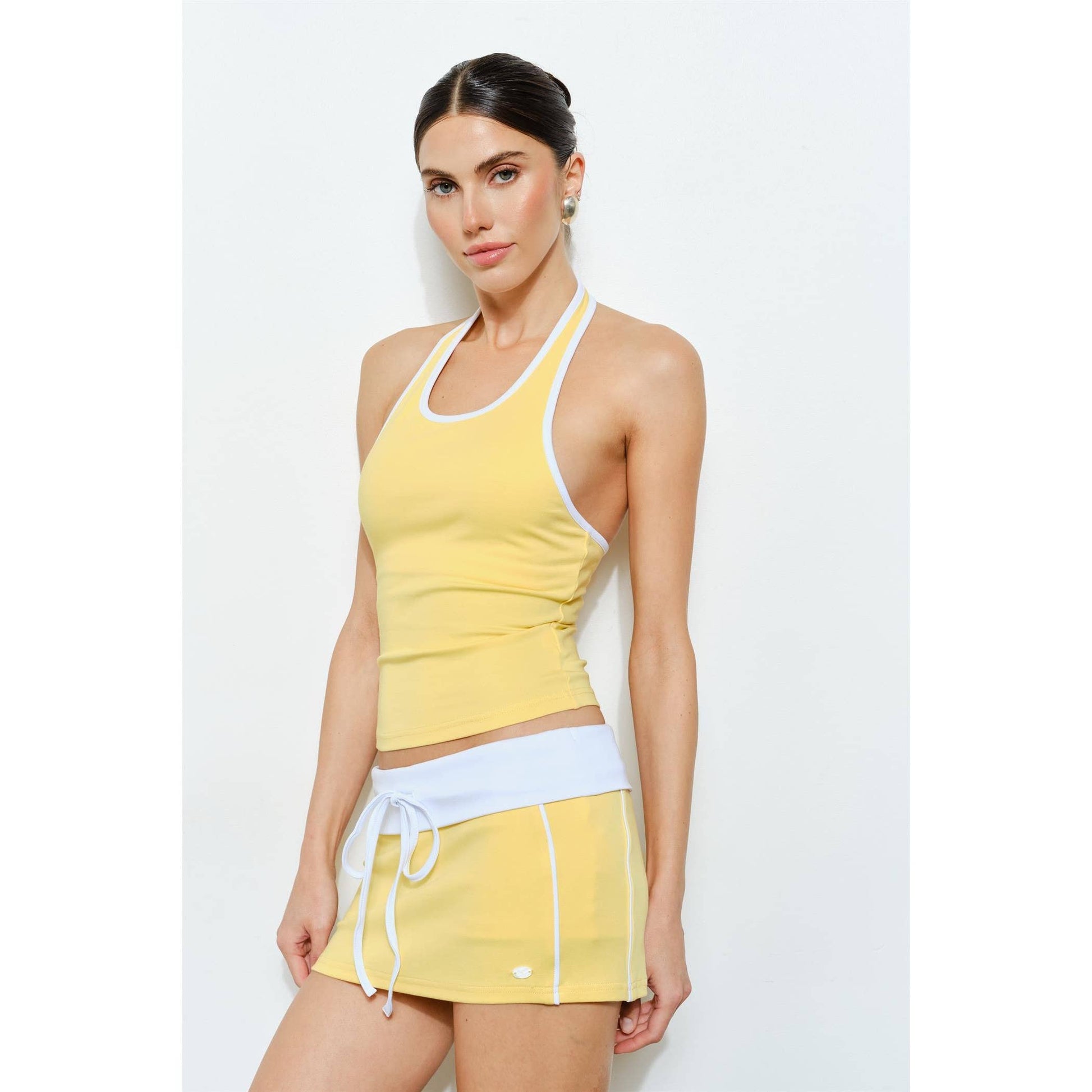 Woman wearing a yellow tank top and skirt set on a white background