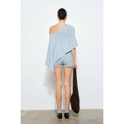 Person wearing a light blue striped outfit holding a brown bag against a white background