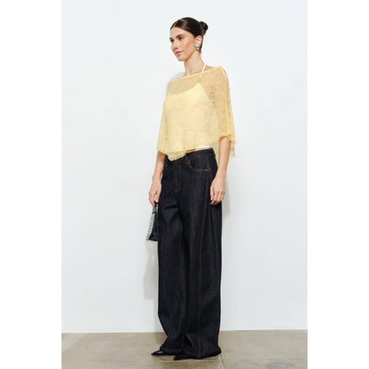 Woman wearing a yellow top and black pants against a white background