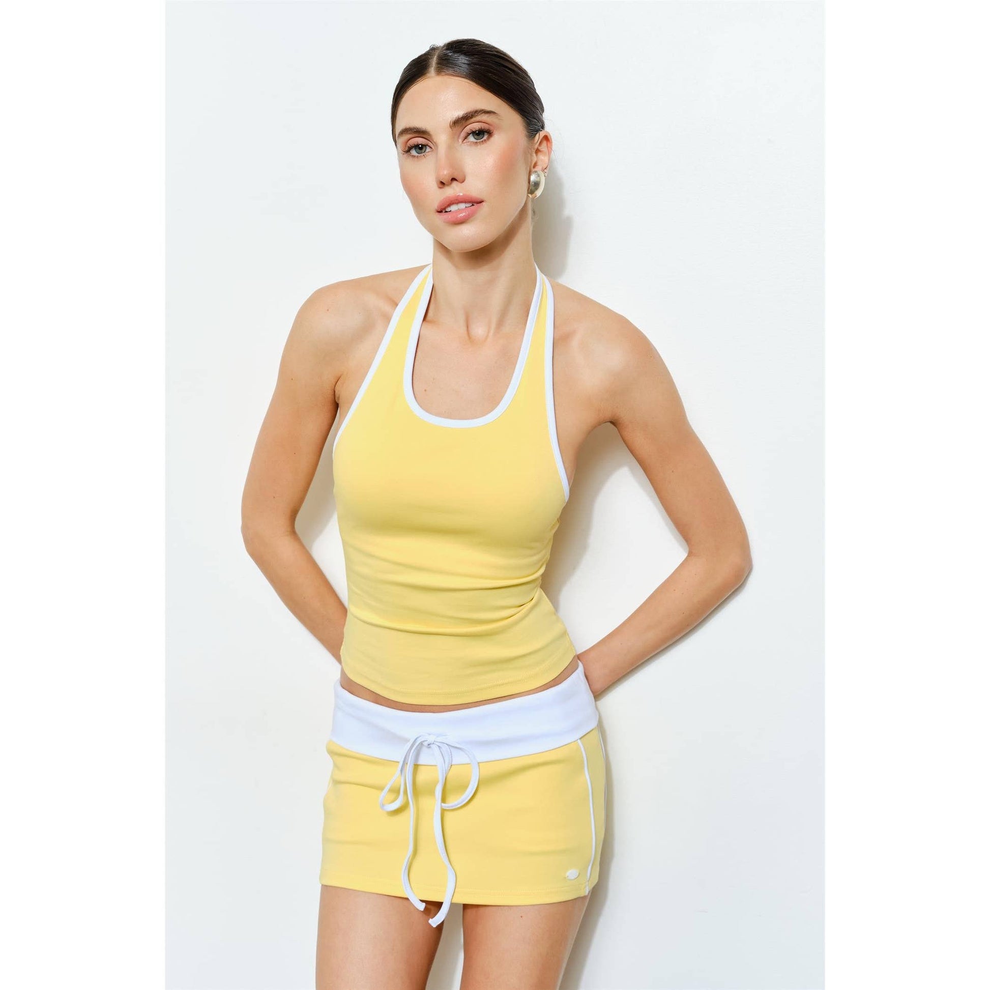 Woman wearing a yellow tank top and shorts set on a white background