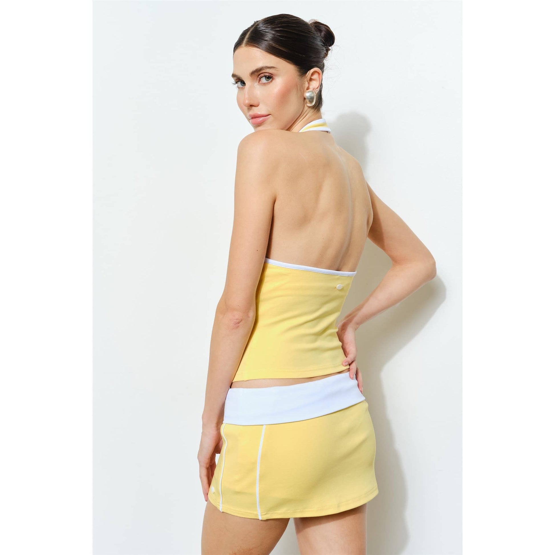 Woman wearing a yellow and white dress against a white background