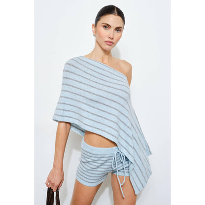 Woman wearing a light blue striped one-shoulder top and shorts on a white background